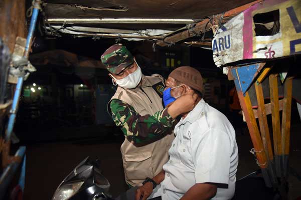 KENAKAN MASKER: Tim dari Satgas Covid-19 Mebidang mengenakan masker kepada seorang warga di Belawan, Selasa (20/10) malam. Dalam razia di kawasan Belawan tersebut, tim membagikan 1.500-an masker gratis.istimewa/sumut pos.