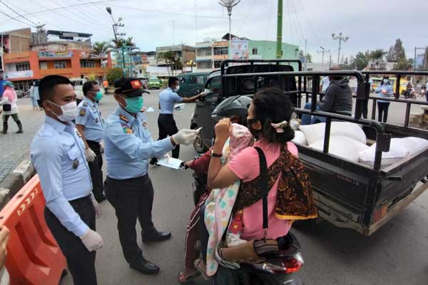 BAGI MASKER: Karutan Kabanjahe, Sangapta Surbakti saat membagikan masker pada pengendara yang melintas, Senin (26/10).Foto:solideo/sumut pos.