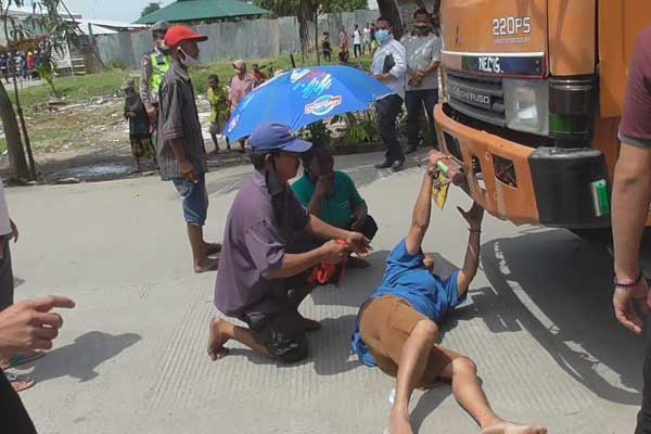 TIDUR DI JALAN:  Seorang ibu nekat tidur di jalan untuk menghalangi truk yang keluar dari pabrik PT MUsim Mas saat melakukan unjuk rasa, Senin (5/10). Warga memprotes keberadaan pabrik tersebut karena menimbulkan polusi dan banjir yang menggenangi rumah warga. 