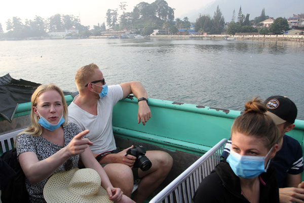 WISMAN: Sejumlah wisatawan mancanegara mengenakan masker saat menyeberang menuju pulau Samosir dari Pelabuhan Ajibata, Jumat (20/9).