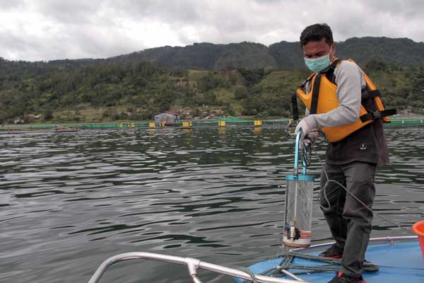 SAMPEL: Agusmanto Sihombing, Asisten Manager Lingkungan RSI, sedang mengambil air Danau Toba sebagai sampel untuk diuji di lab Ajibata. triadi wibowo/sumut pos.