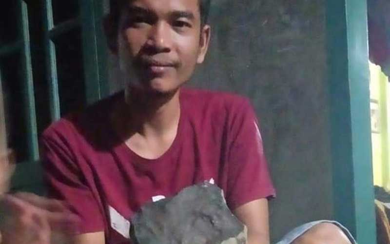 METEOR: Josua Hutagalung saat menunjukkan batu meteor yang jatuh menimpa atap rumahnya.