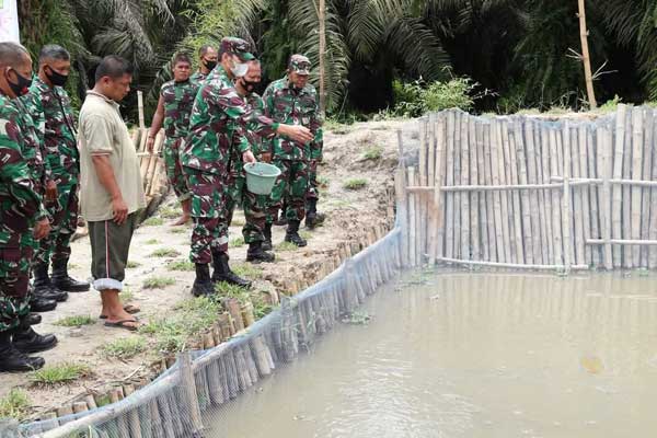 BERI MAKAN IKAN:  Dandim 0208/AS, Letkol Inf Sri Marantika Beruh memberi makan ikan lele yang ada di belakang Makodim, Minggu (15/11).