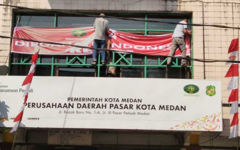 PASANG SPANDUK: Pekerja sedang memasang spanduk PD Pasar Petisah di Jalan Petisah Medan, beberapa waktu lalu.