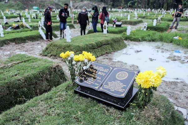 ZIARAH: Warga berziarah di areal pekuburan Covid di Simalingkar. Sampai saat ini, Pemerintah Kota Medan belum memberikan uang santunan kematian bagi korban Covid-19. 