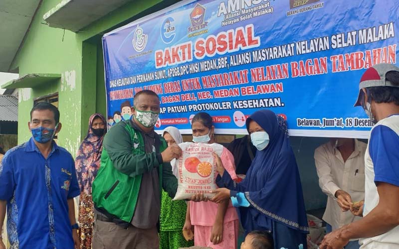 SERAHKAN: Kepala Dinas Kelautan dan Perikanan Provinsi Sumut, Mulyadi Simatupang didamping pengurus HNSI Sumut serahkan bantuan sembako. kepada masyarakat nelayan di Kelurahan Bagan Deli, Belawan, Jumat (18/12). prans/sumut pos.