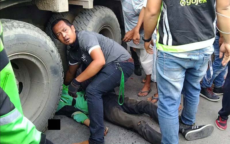 TERLINDAS TRUK: Seorang rekan korban mencoba menyelamatkan rekannya yang terlindas truk di Jalan Marelan Raya, simpang Pasar II, Kelurahan Rengas Pulau, Kecamatan Medan Marelan, Rabu (16/12).fachril/sumut pos.