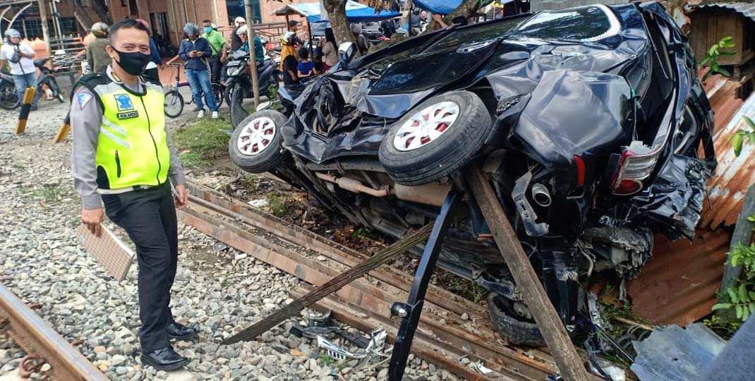 RINGSEK: Petugas kepolisian melakukan olah TKP terhadap kendaraan roda empat yang ringsek setelah ditabrak kereta api di perlintasan Jalan Kakap Binjai, baru-baru ini.