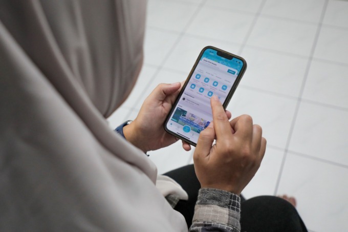 Seorang Ibu rumah tangga yang sedang melakukan pembayaran tagihan listrik pada aplikasi PLN Mobile.