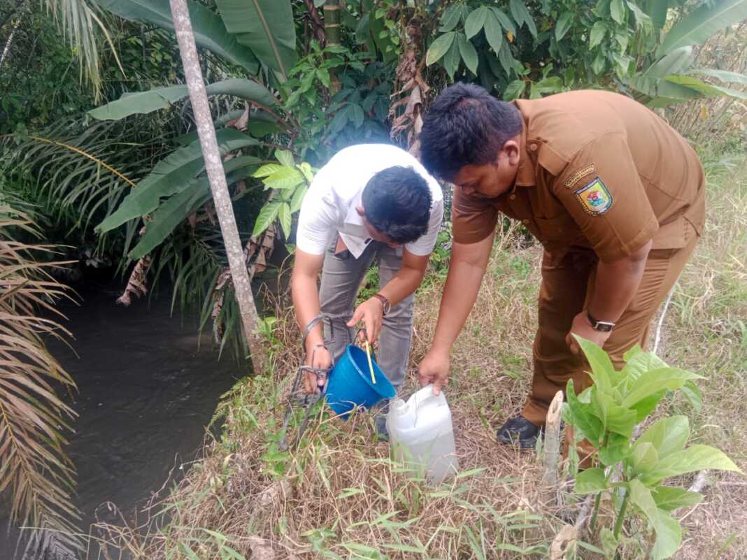 TINJAU: Kabid Pencemaran dan Limbah Dimas Lingkungan Hidup kabupaten Serdang Bedagai Roy R.Sihombing bersama salah satu warga sedang mengambil sampel air sungai yang diduga terdampak limbah. ( FADLY/SUMUT POS)