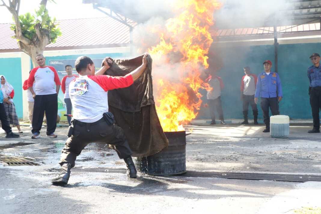 Salah satu Peserta yang sedang melakukan praktik langsung penanganan pemadaman api dengan kain basah saat keadaan darurat.