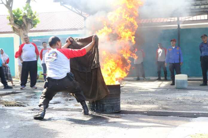 Salah satu Peserta yang sedang melakukan praktik langsung penanganan pemadaman api dengan kain basah saat keadaan darurat.