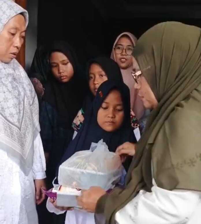 Noery Sitepu (kanan) menyerahkan bingkisan dan santunan kepada anak-anak yatim dalam acara peringatan Hari Asyura sekaligus HUT Arisan Keluarga Besar H Muhammad Syarif Simatupang di Perumahan Rorinata Residence Tahap III Blok C3 Nomor 10 Sei Mencirim, Deliserdang, Minggu (6/7/2025)