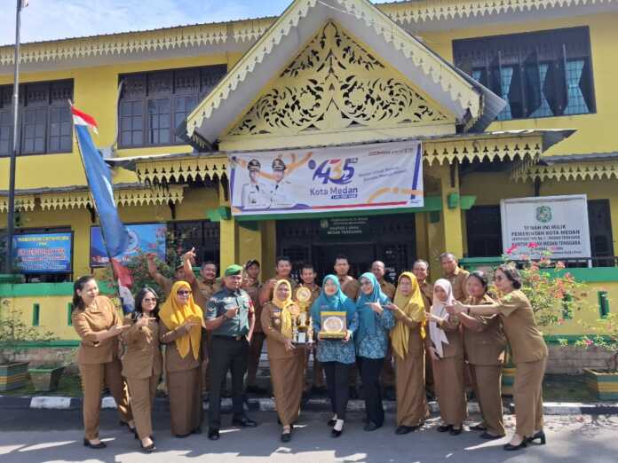 Lurah Medan Tenggara Nurdamayanti Siregar (7 dari kanan) bersama ASN dan Babinsa, Bhabinkamtibmas, Kader PKK, dan Kepling dengan Piala Juara II Kelurahan Terbaik Tingkat Kota Medan di halaman Kantor Kelurahan. (Foto: Tomi Sanjaya Lubis/Sumut Pos)