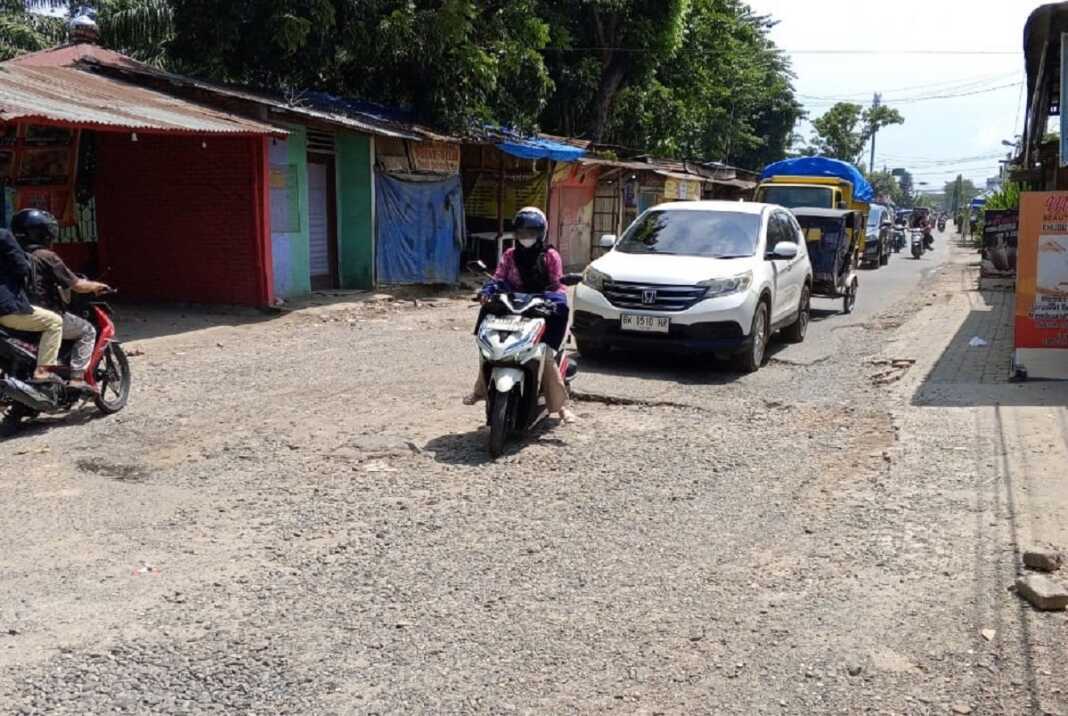 JALAN RUSAK: Kendaraan melintasi jalan di salah satu kawasan Tanjungmorawa, kemarin