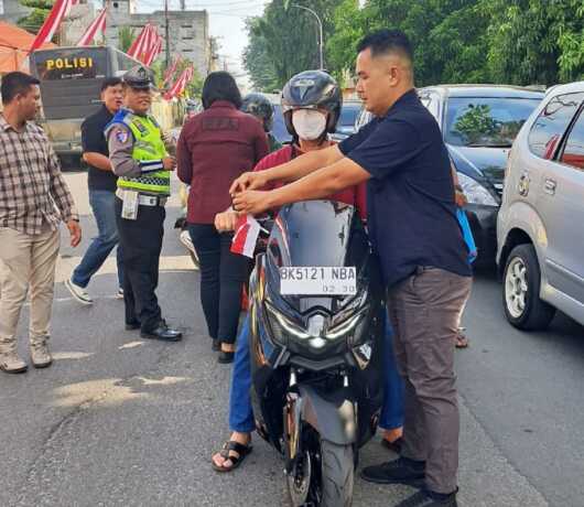BAGIKAN BENDERA: Jajaran Satreskrim Polres Tebingtinggi membagikan Bendera Merah Putih kepada pengguna kendaraan sepeda motor di Jalan Pahlawan Kota Tebingtinggi.