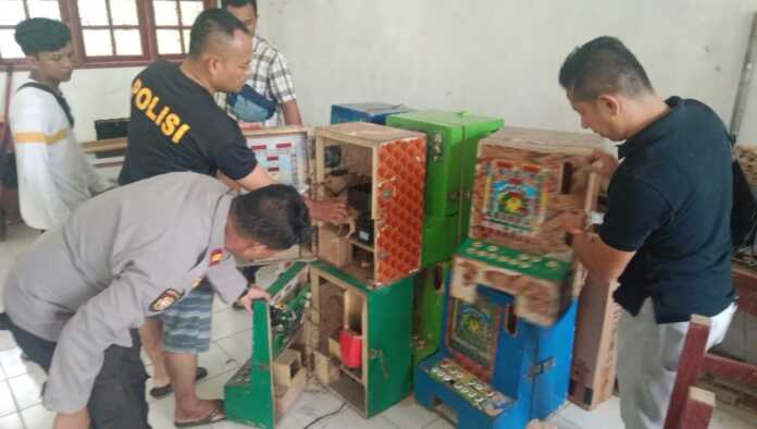 AMANKAN: Personel Polsek Bahorok saat mengamankan mesin judi dari dalam kelas pada unit sekolah yang tidak lagi aktif.