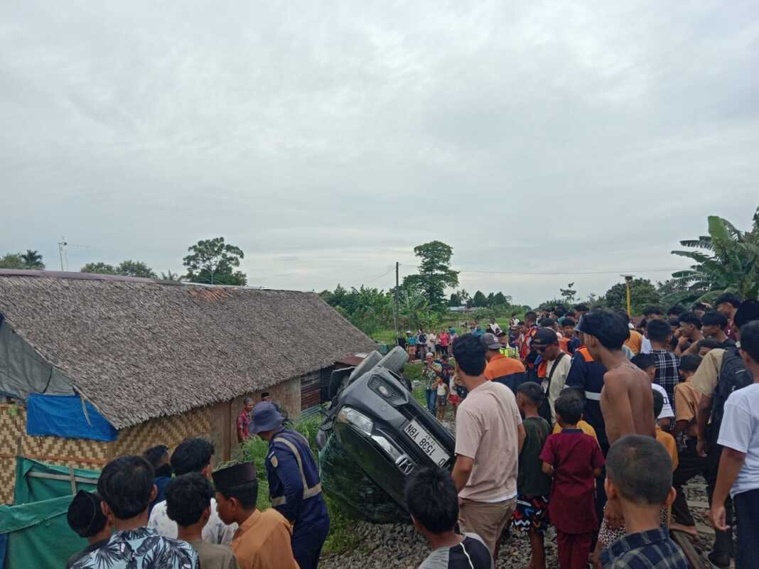 EVAKUASI KORBAN: Warga saat mengevakuasi korban kecelakaan KA U51 Sri Bilah menyeret sebuah mobil Honda Mobilio di perlintasan tanpa palang pintu Gang Sentosa Desa Tumpatan Kecamatan Beringin Kabupaten Deliserdang, Jumat (24/10) sekira pukul 13.00 WIB.