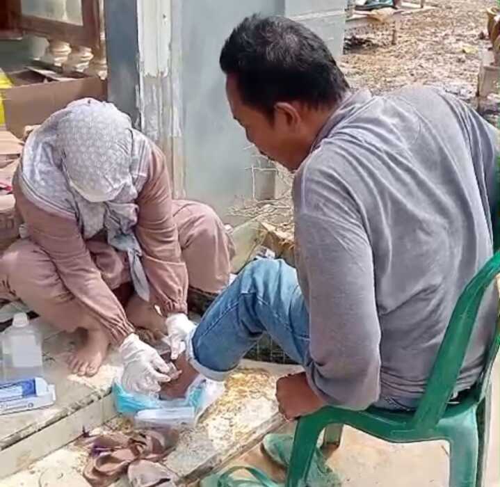 Petugas medis Yayasan Harapan Generasi Madani dan Himpaudi Percut Sei Tuan, membantu korban banjir yang mengalami luka di kakinya.