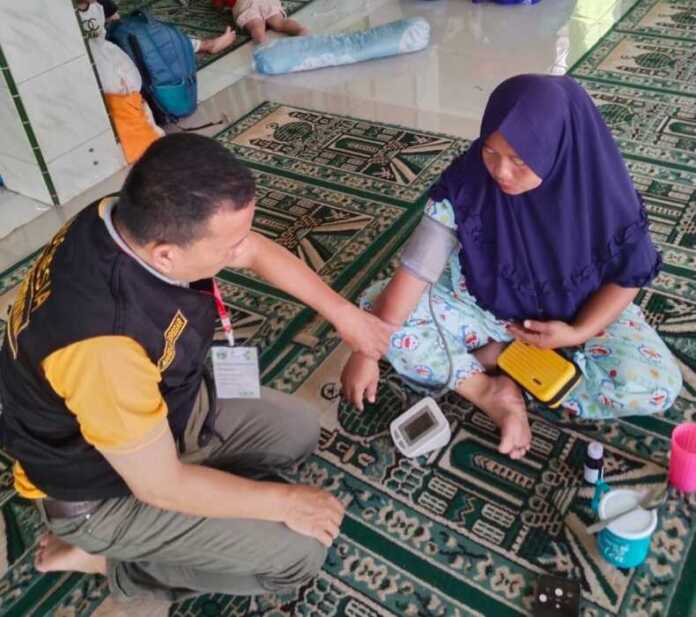 PERIKSA: Tim medis RS Haji Medan saat memeriksa kesehatan pengungsi bencana banjir dan longsor di Sibolga.