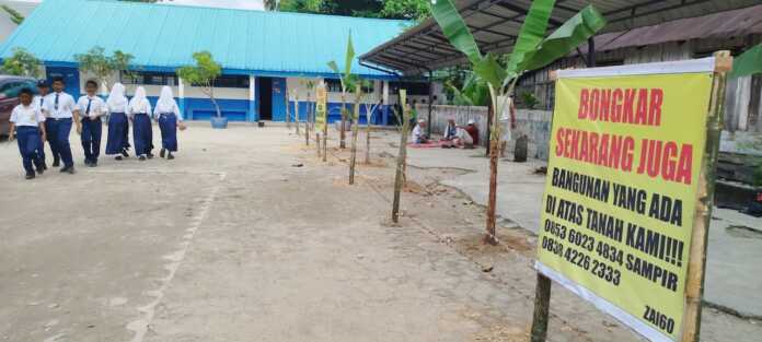 PASANG SPANDUK: Keluarga ahli waris Djiwo Kromo memasang spanduk di komplek SMPN 1 Rantau Utara (fajar)