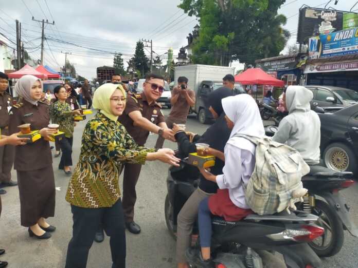 BAGIKAN: Kepala Kejaksaan Negeri Dairi Bima Yudha bersama Ketua Ikatan Adyaksa Dharmakarini (IAD) Tuti Bima, membagikan menu berbuka puasa kepada pengendara melintas di depan Kantor Kejaksaan Dairi, Kamis (12/3).RUDY SITANGGANG/SUMUT POS.