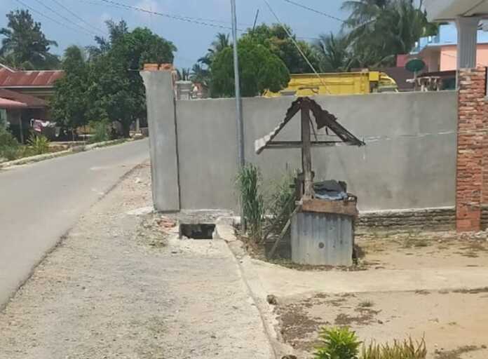 PAGAR RUMAH: Bangunan pagar rumah diduga melewati parit ruas jalan yang saat ini tengah dikerjakan di Dusun 3, Kamis (26/3). (Liberti H Haloho)