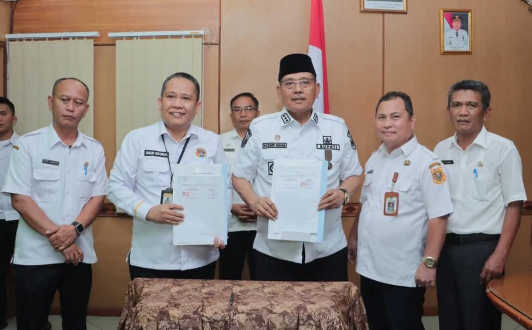TUNJUKKAN: Bupati Dairi Vickner Sinaga dan Kepala Kantor BPN Dairi Daud Wijaya Sitorus, menunjukkan naskah nota kesepakatan usai melakukan penandatanganan, Rabu (4/3).SUMUT POS/istimewa.