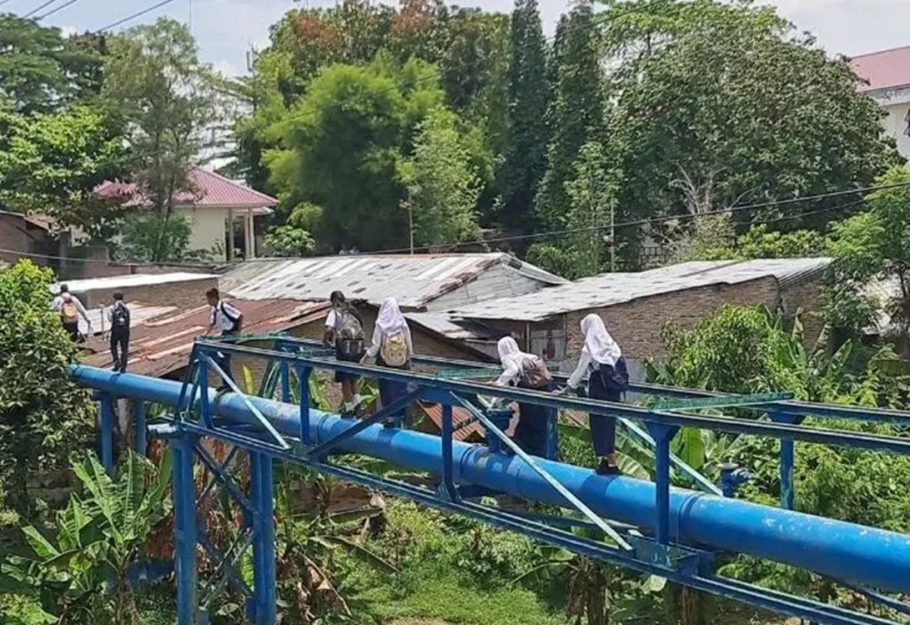 MENITI PIPA: Pelajar sekolah saat berjalan meniti pipa untuk berangkat sekolah.