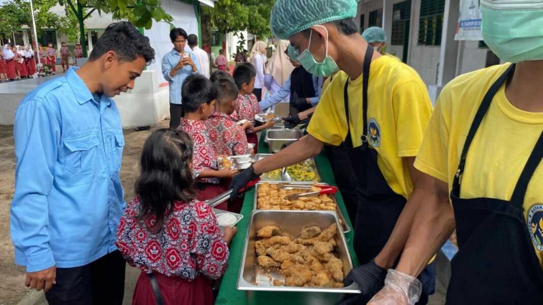 LAYANI : Petugas SPPG Firdaus I melayani siswa SDN 107967 Pelintahan saat pembagian MBG dengan sistem prasmanan, Rabu (8/4).( Fad )