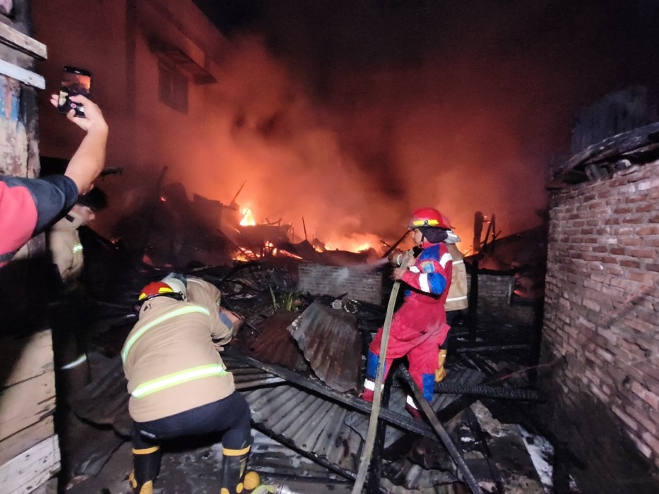 PADAMKAN API: Tim pemadam kebakaran berjibaku memadamkan kobaran api di lokasi kebakaran di Jalan Thamrin depan Kantor Camat Tebingtinggi Kota, Minggu (3/5) dini hari. (Azzan)