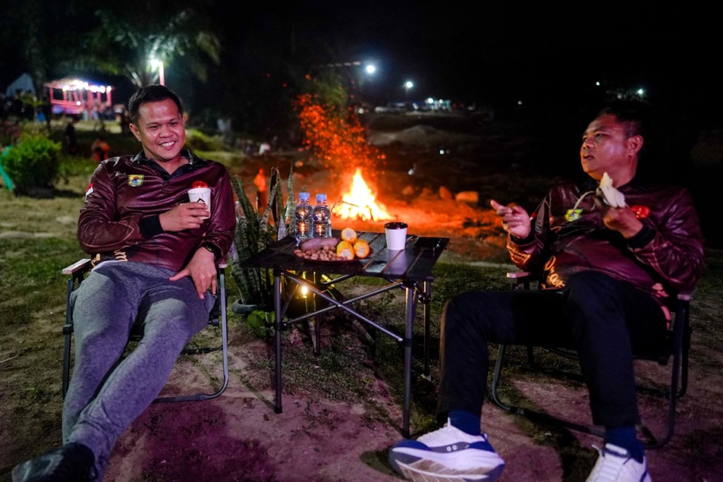 MALAM KEAKRABAN:  Ketua Mabicab Gerakan Pramuka Sergai, Kakak H Darma Wijaya dan Ketua Kwarcab Gerakan Pramuka Serdang Bedagai, Kakak H Adlin Tambunan saat  menikmati suasana hangat malam keakraban di pinggiran Sungai Bahbolon, penuh canda dan kebersamaan di bawah cahaya api unggun, Sabtu (2/5/2026). ( Fad )