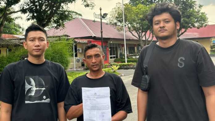 Jukir Dilaporkan LAPORAN: Korban Dedi (tengah) menunjukkan bukti laporan polisi atas dugaan penganiayaan.(Foto dari massa aksi/Sumut Pos)