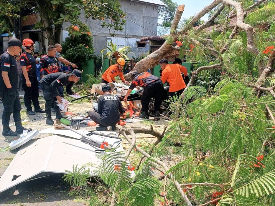 TUMBANG: Petugas BPBD Binjai melakukan pembersihan pohon yang tumbang timpa pedagang betor jualan bakso.(Foto dari masyarakat/Sumut Pos)