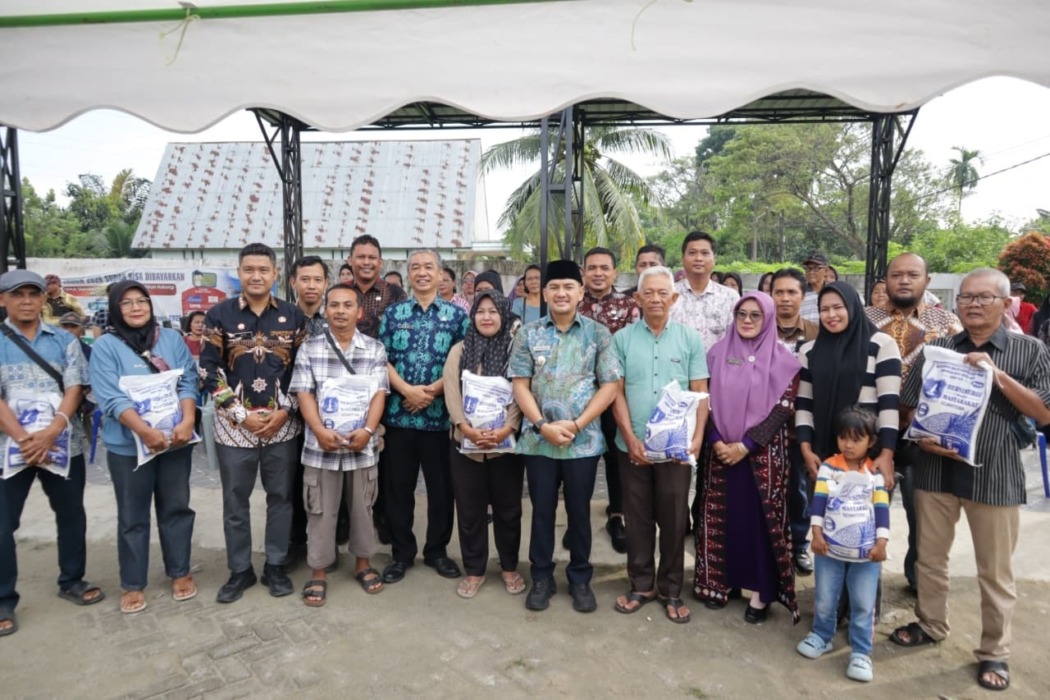BERSAMA: Wali Kota Tebingtinggi H Iman Irdian Saragih didampingi Sekda Erwin Suheri Damanik, Plt Kepala Dinas Sosial Tigahara Hasibuan, serta camat dan lurah berfoto bersama warga usai meninjau penyaluran bantuan beras premium tahap pertama kepada keluarga kurang mampu di Kelurahan Pinangmancung dan Kelurahan Tanjung Marulak, Jumat (10/7/2026).
