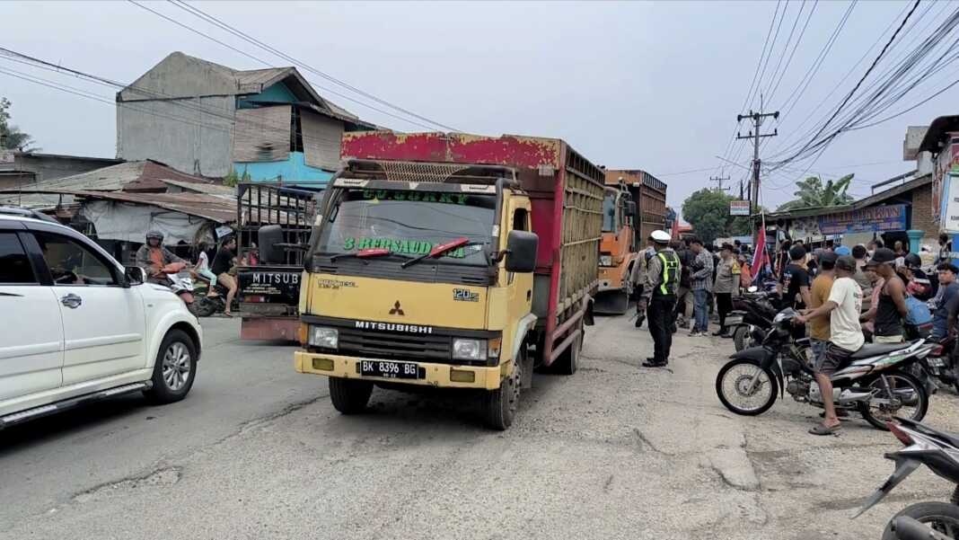 MELINTAS: Truk bermuatan kembali melintas usai masyarakat membubarkan diri dari aksi blokir jalan penghubung Kecamatan Binjai dengan Langkat. (Teddy Akbari/Sumut Pos)