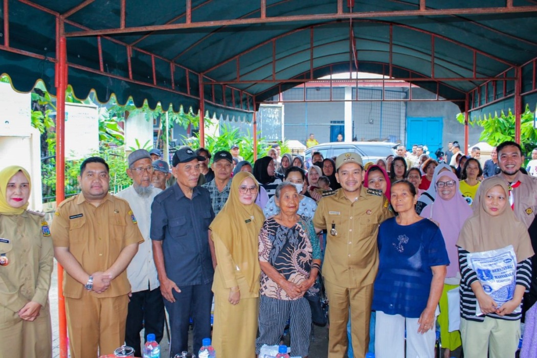 BERSAMAL Wali Kota Tebingtinggi, Iman Irdian Saragih, berfoto bersama warga penerima bantuan pangan berupa beras di Kelurahan Tambangan, Kecamatan Padang Hilir, Senin (26/10).Azan Purba/ sumutpos.