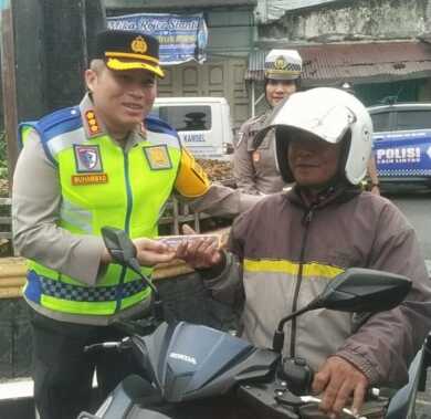 Kapolresta Deliserdang Kombes Pol Muhammad SH memberikan brosur sosialisasi Ops Patuh Toba di Simpang Bakaran Batu, Lubukpakam sebari mengatur arus lalulintas.
